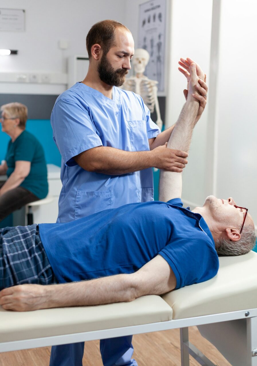 Physiotherapist giving chiropractic massage to elder man